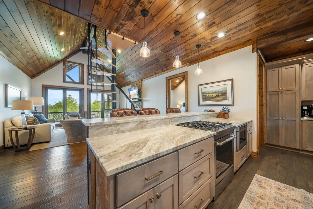 A spacious open kitchen with a central island, spiral staircase, and adjacent seating area, offering a welcoming atmosphere for cooking, entertaining, and relaxing. The layout encourages communal meals and celebrations.
